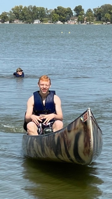 student canoeing and swimming